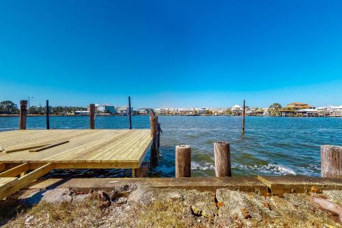 a dock on the water with a city in the background at Bay Dream Believer in Dauphin Island