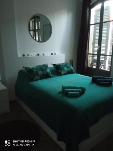 - une chambre avec un grand lit vert et un miroir dans l'établissement Les terrasses, à Arles