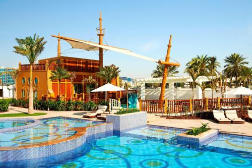 a pool at a resort with palm trees and a building at The St. Regis Abu Dhabi in Abu Dhabi