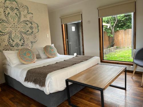 Un dormitorio con una cama y una mesa y una ventana. en Kayu Loft, en Puerto Natales