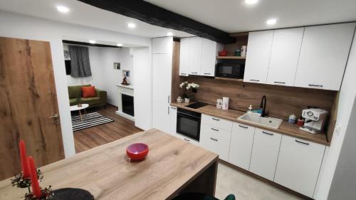 a kitchen with white cabinets and a wooden table at Вивиан - модерна вила за гости in Reselets