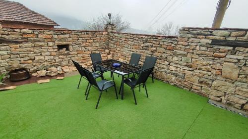 a patio with a table and chairs and a stone wall at Вивиан - модерна вила за гости in Reselets
