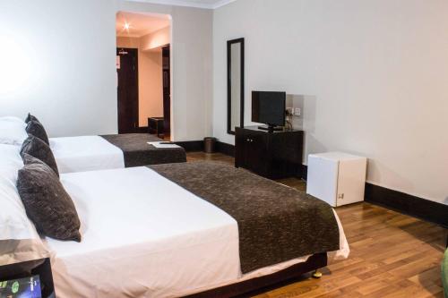 a hotel room with two beds and a television at Protea Hotel by Marriott Lusaka in Lusaka
