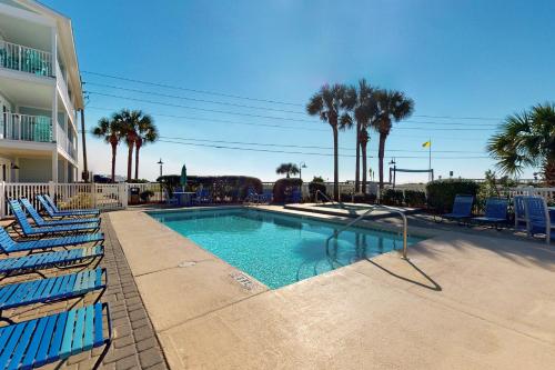 a swimming pool with blue lounge chairs and palm trees at Summerspell 103 in Destin