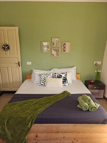 a bedroom with a large bed with green walls at SOLS Backyard in Arambol