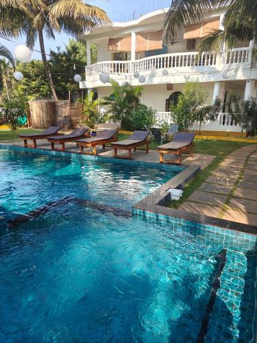 a swimming pool with chairs and a building at SOLS Backyard in Arambol