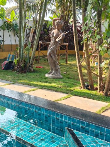 a statue of a woman standing next to a swimming pool at SOLS Backyard in Arambol