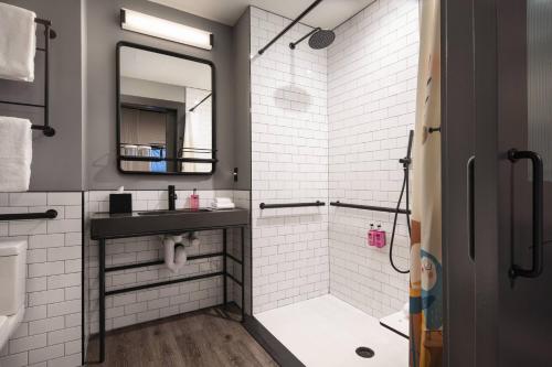 a bathroom with a shower and a sink and a mirror at Moxy Nashville Vanderbilt Area in Nashville