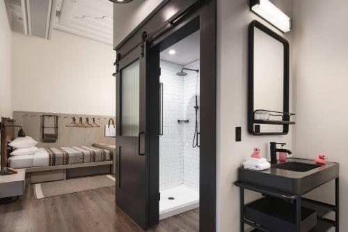 a bathroom with a sink and a shower with a mirror at Moxy Nashville Vanderbilt Area in Nashville