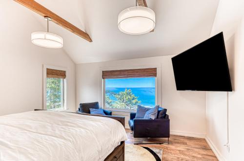 a bedroom with a bed and two chairs and a flat screen tv at Oceanside Skies - Main House in Oceanside