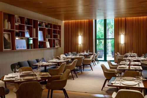 a dining room with tables and chairs and a large window at Boa Vista Surf Lodge in Pôrto Feliz