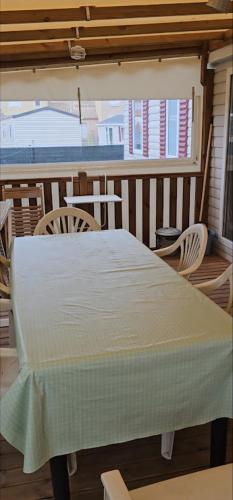 - une table et des chaises blanches sur une terrasse couverte dans l'établissement mobil home grand confort, à Valras-Plage