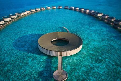 a swimming pool with chairs in the water at The Ritz-Carlton Maldives, Fari Islands in North Male Atoll