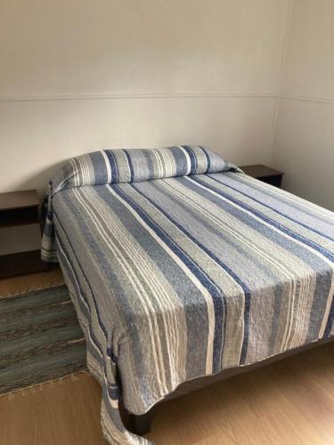 a bed with a blue and white striped blanket on it at Casa Relmu in Puerto Varas