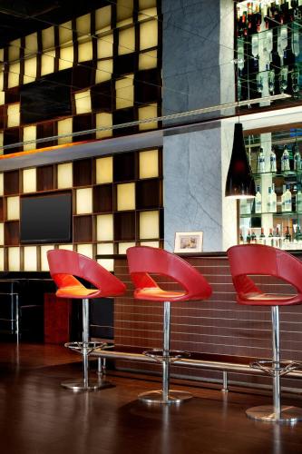 two red chairs sitting in front of a bar at Le Meridien Coimbatore in Coimbatore