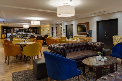 a restaurant with a couch and tables and chairs at Protea Hotel by Marriott Cape Town Durbanville in Bellville