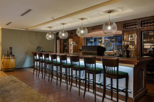 a bar with a row of stools in a room at Protea Hotel by Marriott Cape Town Durbanville in Bellville