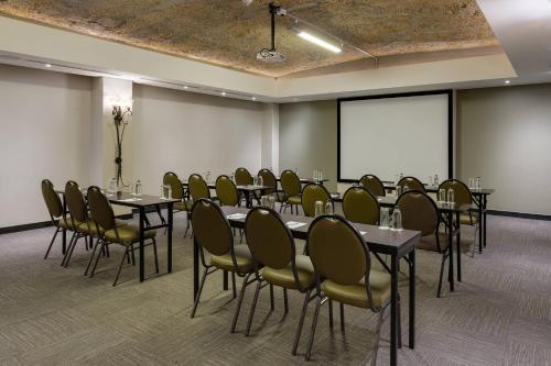 a conference room with tables and chairs and a projection screen at Protea Hotel by Marriott Cape Town Durbanville in Bellville