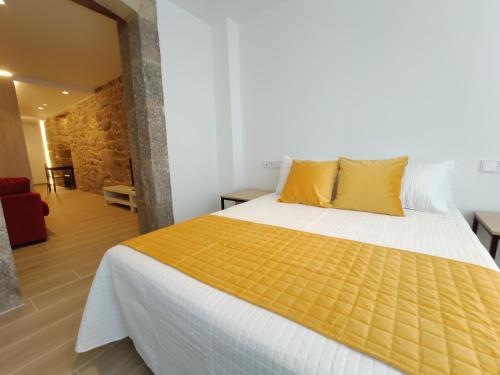 a bedroom with a large bed with yellow pillows at Apartamentos A pousa do Asma in Chantada