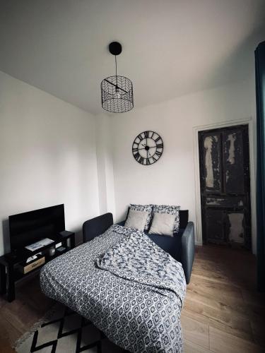 une chambre avec un lit et une horloge au mur dans l'établissement Saint Nicaise - Centre historique de Rouen, à Rouen