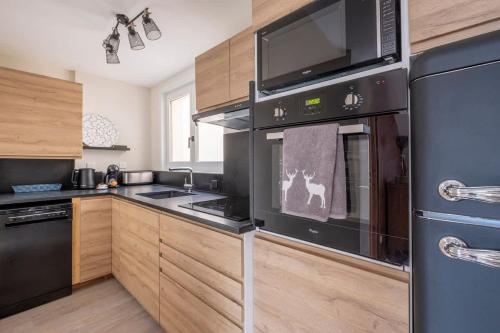 - une cuisine avec des appareils noirs et des armoires en bois dans l'établissement L'Appart 52, magnifique duplex en plein coeur de Chamonix-Mont-Blanc, à Chamonix-Mont-Blanc