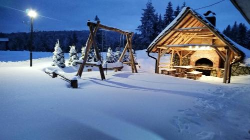 a playground in the snow next to a cabin at Vila Šapat šume in Ljuboš