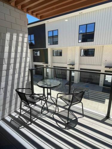 a patio with a table and chairs on a balcony at Stylish and Sleek Auckland Stay in Auckland