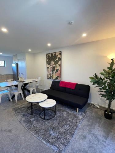 a living room with a black couch and two tables at Urban Auckland Sanctuary in Auckland