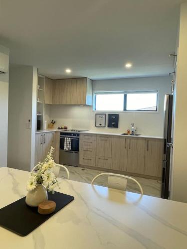 a kitchen with a table with a vase of flowers on it at Urban Auckland Sanctuary in Auckland