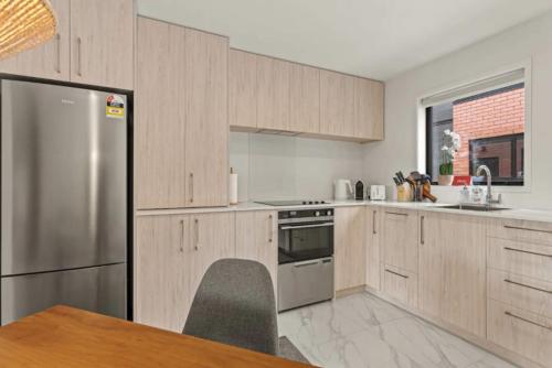 a kitchen with wooden cabinets and a stainless steel refrigerator at 11 Te Kanawa Haven in Auckland