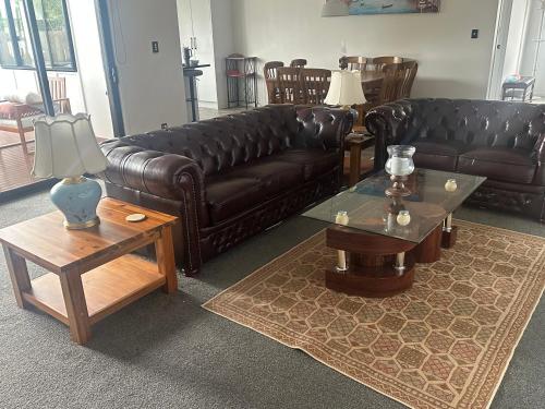 a living room with a leather couch and tables at Trendy Bungalow in the Heart of Rotorua in Rotorua