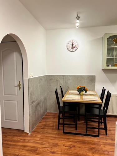a dining room table with chairs and a clock on the wall at Penzion Mánes in Krabčice