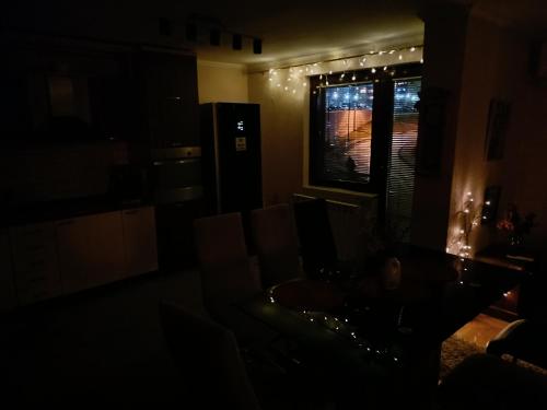 a dark room with a couch and a window with lights at Apartment Imamović in Vogošća