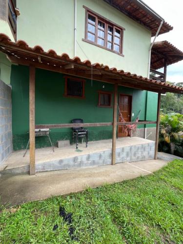 a green house with a patio in front of it at Casa Refúgio da Paz in Lumiar