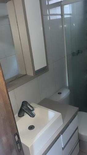 Un baño blanco con lavabo y ducha. en Quarto Aconchegante - Suíte, en Camboriú