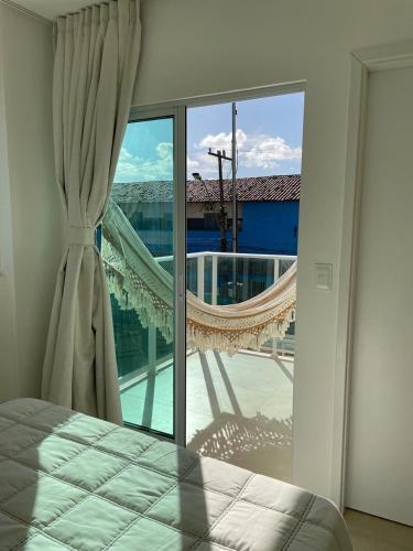 a bedroom with a bed and a large glass window at Casa Beira Mar com Piscina Maragogi - Amar & Mar in Maragogi