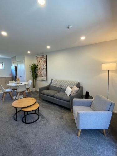 a living room with a couch and chairs and a table at Chic Auckland Getaway in Auckland