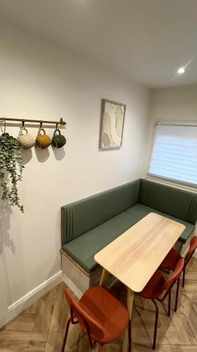 a room with a green bench and a table and chairs at DisneyLand et Paris - Appartement Cosy in Noisiel