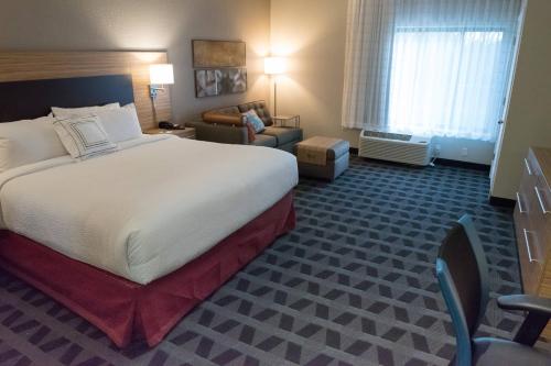 a hotel room with a large bed and a chair at TownePlace Suites by Marriott Battle Creek in Battle Creek