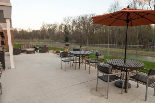 a patio with tables and chairs and an umbrella at TownePlace Suites by Marriott Battle Creek in Battle Creek