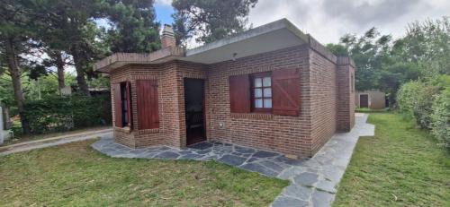 una pequeña casa de ladrillo con puertas rojas en un patio en Casa Ostende Junin, en Ostende