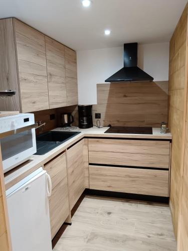 une cuisine avec des armoires en bois et un réfrigérateur blanc dans l'établissement Karibu, à Saint-Gervais-les-Bains