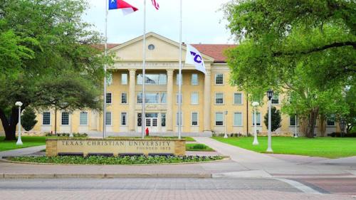 a large yellow building with a sign in front of it at Clarion Pointe - Fort Worth Arlington West in Fort Worth