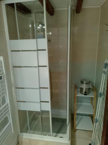 a glass shower door in a room with a table at petite maison cosy in Auneau
