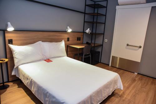 a bedroom with a large white bed and a desk at ibis Tangará Da Serra in Tangara da Serra