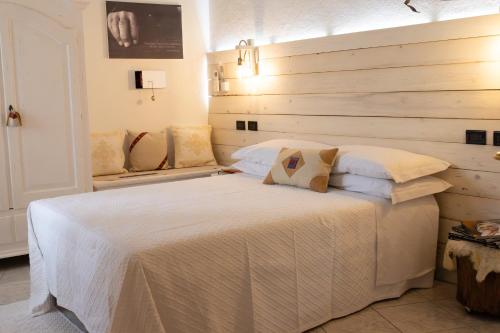 a bedroom with a white bed with a wooden wall at Domo de Ciu Nenneddu in Oliena