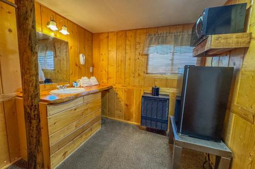 a bathroom with a sink and a mirror and a tv at Chinook Winds Lodge in Dubois