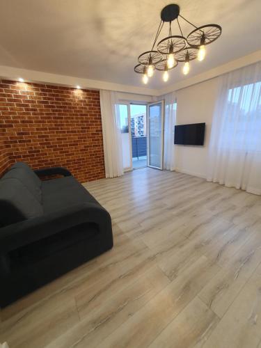 a living room with a black couch and a brick wall at Apartament MONINI - przestronny, miejsce garażowe, FV in Kielce