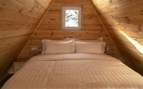 a bed in a wooden cabin with a window at Villariba eco-camp in Almaty
