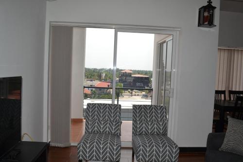 two chairs in a living room with a large window at Luxury Condo in Negombo in Negombo